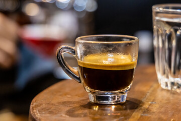A glass of Espresso coffee on a wooden table. Blurred background.