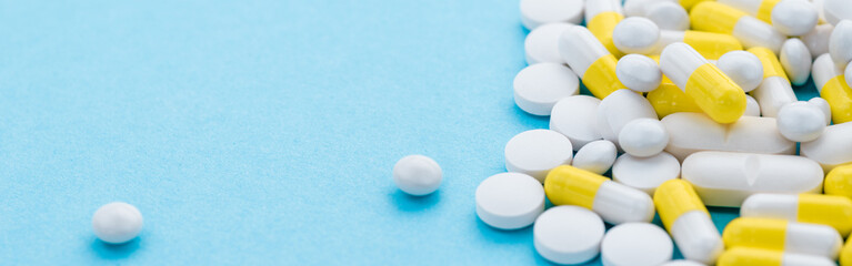 Pile of different pills and pills in different colors on a blue background with copy space....