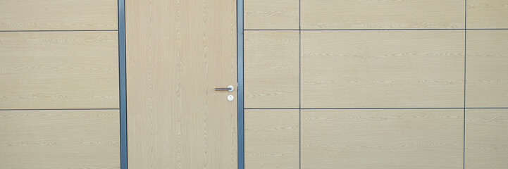 Interior of long wall with light brown door airport or train station