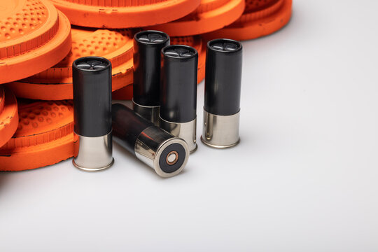 Black shotgun shell bullets with clay shooting target on white background