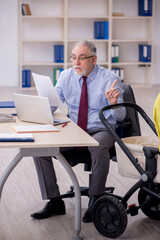 Old male employee looking after new born at workplace
