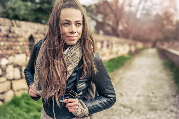 Portrait of a beautiful young woman with long brown hair wearing a black leather jacket and scarf. Toned