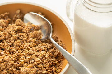 Granola in yellow plate and almond milk closeup