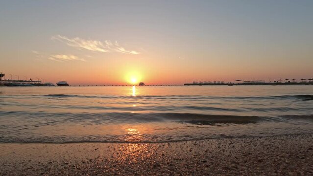 Small maves moving on the beach while the sunset creates a colorful horizon