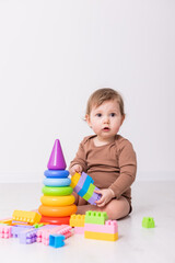 adorable baby in brown shirt playing with toys, card, banner, space for text
