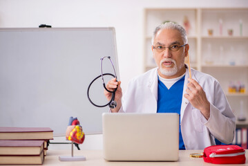 Old male doctor cardiologist working in the clinic