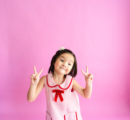Pretty little girl giving two peace sings with a smile.