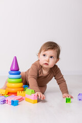 adorable baby in brown shirt playing with toys, card, banner, space for text