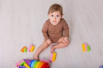 adorable baby in brown shirt playing with toys, card, banner, space for text