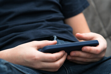 Male hands play videogames on smartphone closeup. Guy using mobile phone to play game or watch online video content.