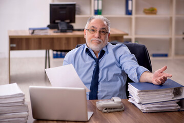 Obraz premium Old male employee and too much work in the office