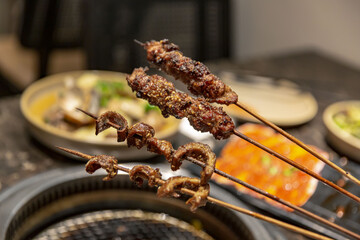 Authentic Uyghur Lamb Skewers and intestines with Fresh Ingredients, in a Traditional Restaurant, selective focus