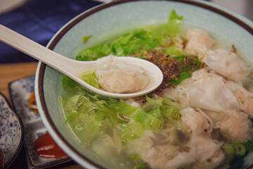 Delicious Asian Wonton Noodle Soup with Crispy Shallots in a Restaurant, Served with Wonton Scoop on a Spoon