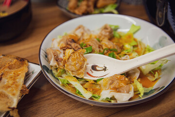 Sichuan Spicy Wonton (Chaoshou) in Red Oil, Scooped on a Spoon, Served in a Restaurant