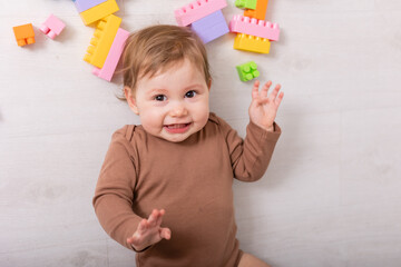 adorable baby in brown shirt playing with toys, card, banner, space for text