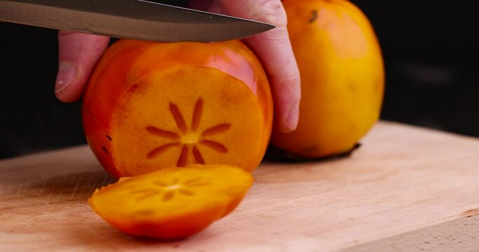 cut old long - lying persimmon with dark spots , delicious homemade persimmon during cutting into slices