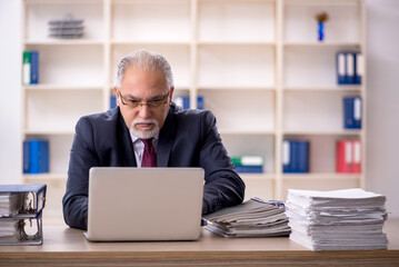 Old male employee sitting at workplace