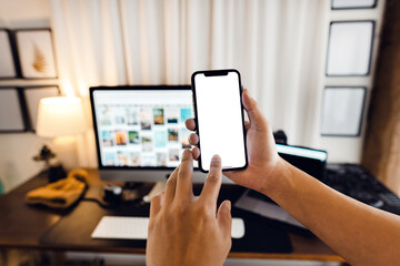 hand holding smartphone with blank screen in home desk