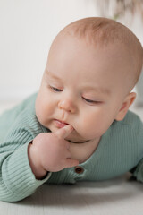 baby in a green jumpsuit learns to crawl on the floor