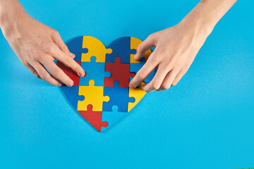 Autistic boy hands holding jigsaw puzzle heart shape. World Autism Awareness Day