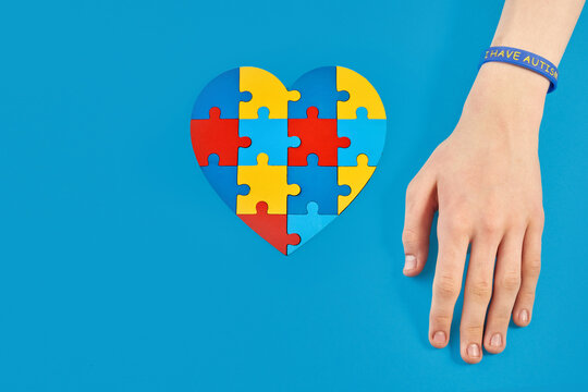 Autistic boy hand and jigsaw puzzle heart shape. World Autism Awareness Day