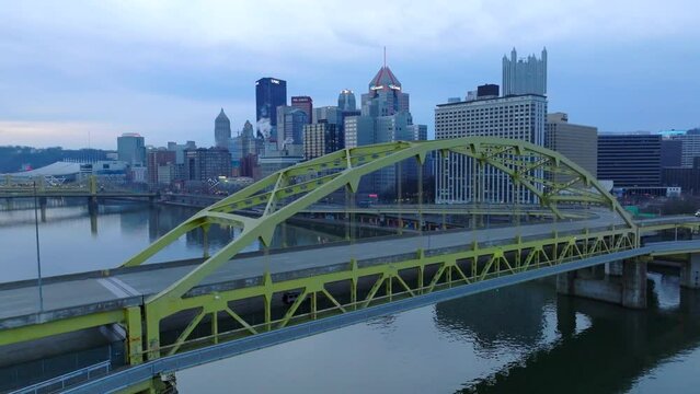 Aerial shot of Fort Duquesne Bridge in Pittsburgh. Beautiful yellow steel contrasts morning light on city skyline.