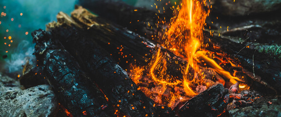 Vivid smoldered firewoods burned in fire close-up. Atmospheric background with orange flame of...