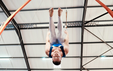 Man, acrobat and gymnastics upside down on rings in fitness for practice, training or workout at...