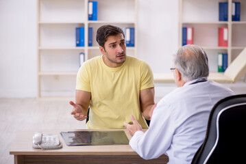 Fototapeta premium Young male patient visiting old male doctor