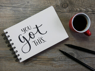 YOU GOT THIS lettering in notebook with cup of coffee and pens