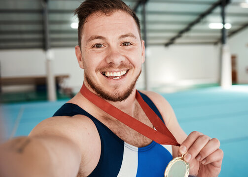 Gymnastics, fitness and male athlete taking a selfie after winning a medal in competition. Sports, smile and portrait of happy male gymnast winner taking a picture after training or practice in arena