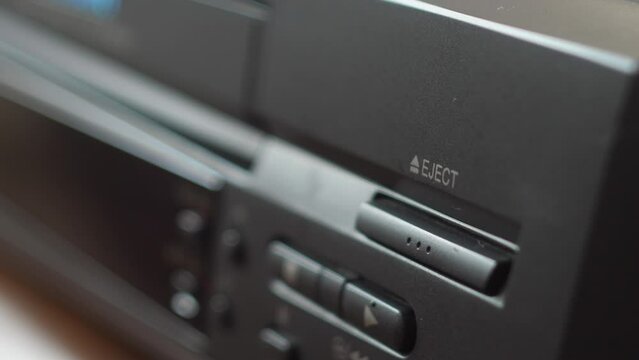 close-up loading a video cassette into the VCR tray. selective focus, shallow depth of field. watching a movie on a video player. vhs cassette