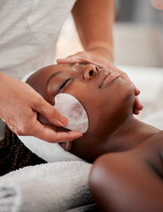 Black woman face, relax and gua sha stone spa treatment of a young female with facial. Skincare, beauty and wellness clinic with client feeling calm and zen from massage and dermatology glow
