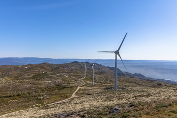 Sustainability theme, view at the top at the Caramulo mountains, amazing view with wind turbines or windmills on top at the mountains, nature and typical fields with vegetation and road, Portugal