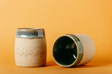 corso di ceramica, bicchieri in ceramica fatti al tornio a mano. sfondo neutro colorato. bicchieri e recipienti per colazione pranzo o cena, tisane, momento di relax
