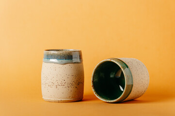 corso di ceramica, bicchieri in ceramica fatti al tornio a mano. sfondo neutro colorato. bicchieri e recipienti per colazione pranzo o cena, tisane, momento di relax
