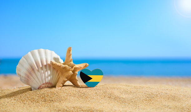 Beautiful beach in the Bahamas. Flag of Bahamas in the shape of a heart and shells on a sandy beach. - Powered by Adobe