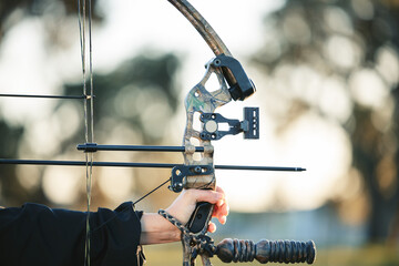 Archery bow closeup and woman hands at shooting range for competition, game or learning in field or...