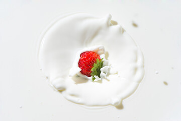 The falling strawberry are splashing into the milk