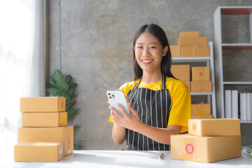 Young pretty asian start up business woman in apron working with online parcel box warehouse...