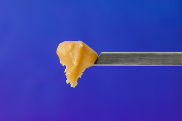 Live Rosin on a dab tool with a blue background - obrazy, fototapety, plakaty