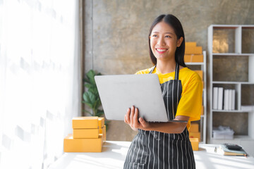 Young pretty asian start up business woman in apron working with online parcel box warehouse selling online product with social media influencer people with subscriber and followers