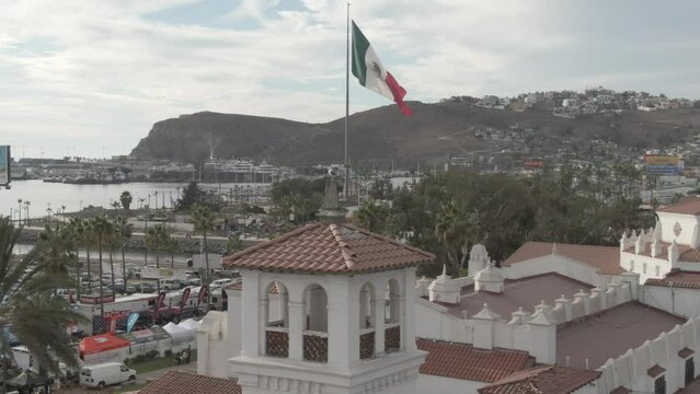 Aerial of tower flag pole and coastline in Ensenada, Mexico with mountains in background