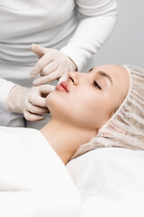 Obraz na płótnie Canvas close-up, female lips. Surgeon, in medical gloves, carefully and slowly injects hyaluronic acid into woman's lips with a syringe. lip augmentation procedure. beauty injections. Plastic surgery.