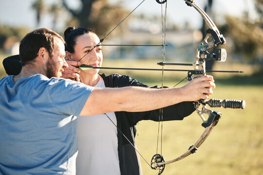 Archery, aim and shooting range sports training with a woman and man outdoor for target practice. Archer and athlete person with focus on field for competition or game with bow and arrow for action
