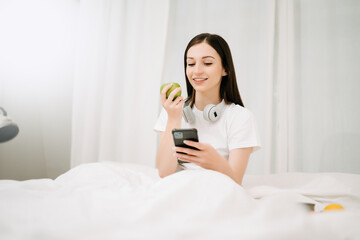 Fototapeta na wymiar Beautiful woman has woken up on a white bed and holding coffee in the morning at home in morning