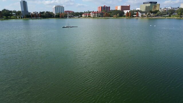 Drone shot over Lake Morton in downtown Lakeland Florida, tilting up to reveal the city skyline