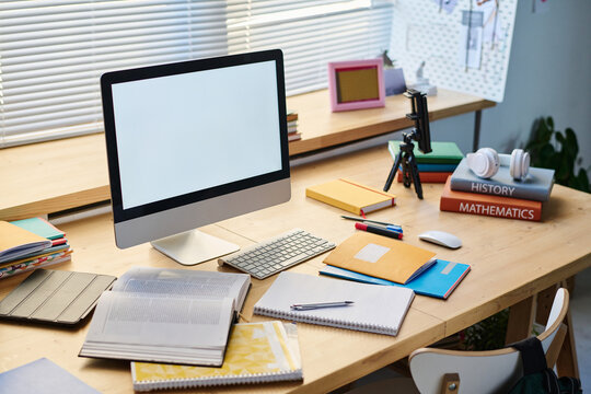 Horizontal image of workplace of teenager with computer monitor and books on it in the room