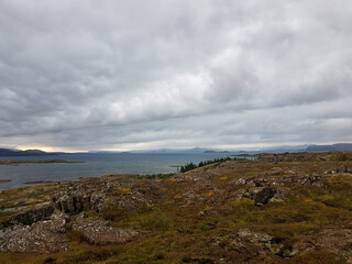 Obraz premium Lake, island and rocks with mountains on the background at Thingvellir National Park in Iceland