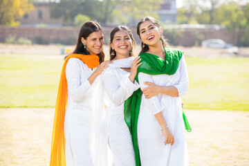 Indian Independence day or Republic day concept. Three happy young beautiful woman wearing traditional white dress standing at park looking at camera.